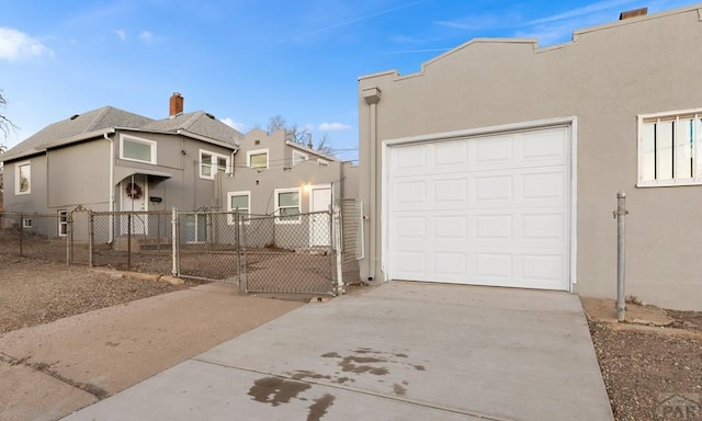 view of front of property with a fenced front yard, a gate, driveway, and stucco siding