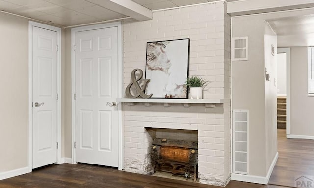 living area with dark wood-style floors, visible vents, a fireplace, and baseboards