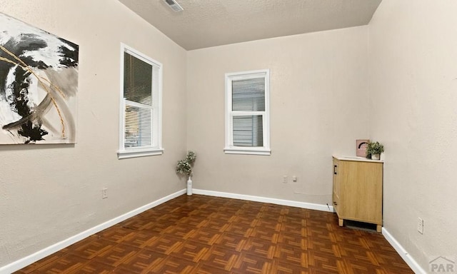 spare room with a textured ceiling, visible vents, and baseboards