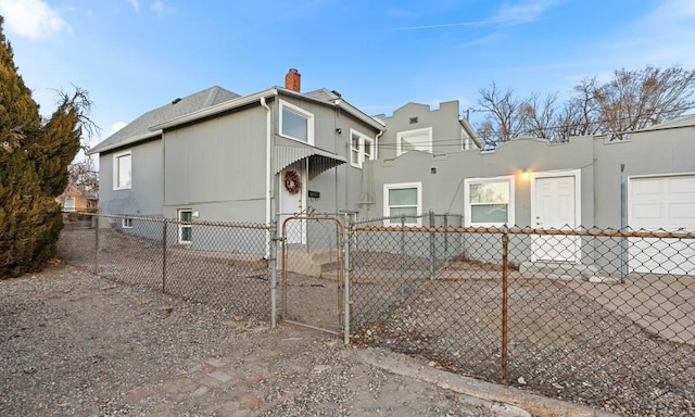 view of side of property with a fenced front yard, a chimney, and a gate