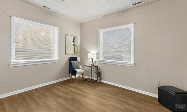 living area with visible vents, baseboards, and wood finished floors