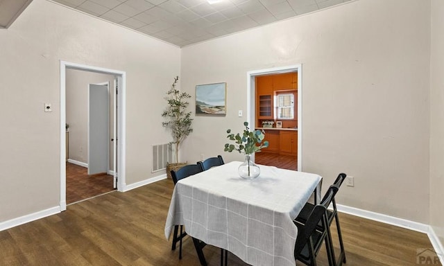 dining space with wood finished floors, visible vents, and baseboards