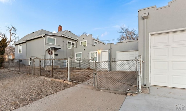 view of front of house with a garage, a fenced front yard, a gate, and stucco siding