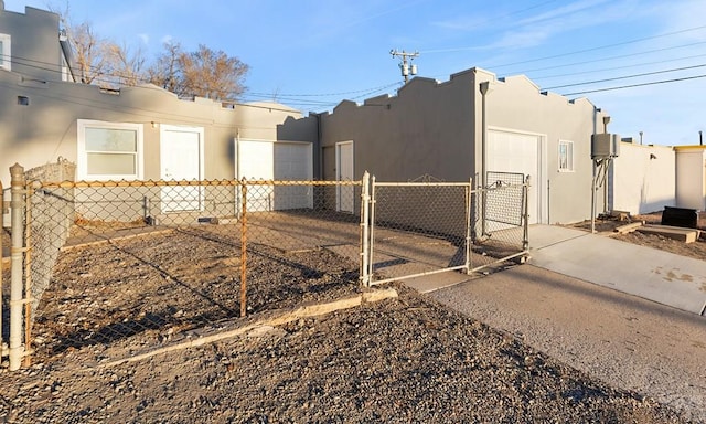 view of home's exterior with driveway, fence, a gate, and stucco siding