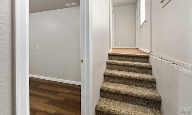 staircase with visible vents, baseboards, and wood finished floors