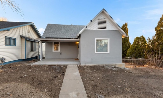 back of house with a patio area, a shingled roof, fence, and stucco siding