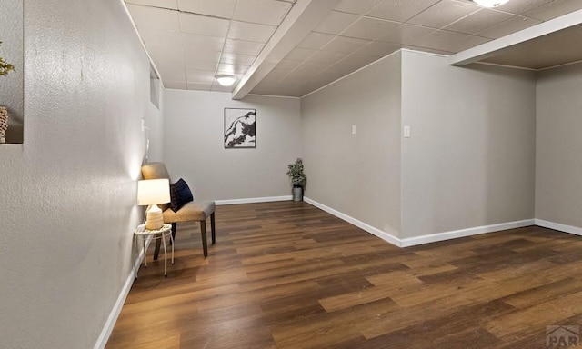 sitting room with a paneled ceiling, baseboards, and wood finished floors