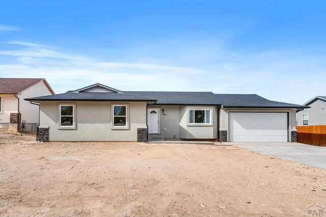 ranch-style home with a garage, concrete driveway, fence, and stucco siding