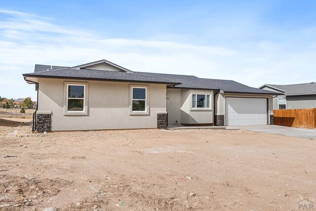 view of front of home with driveway, an attached garage, fence, and stucco siding