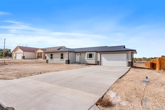 single story home with a garage, concrete driveway, fence, and stucco siding