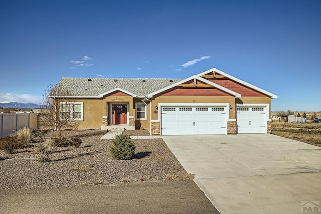 view of front of home with driveway, an attached garage, fence, and stucco siding