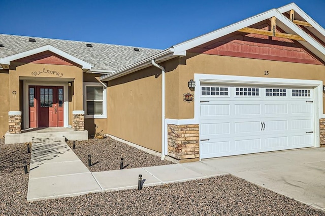 view of front facade featuring driveway, stone siding, roof with shingles, an attached garage, and stucco siding