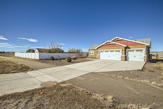 view of side of property featuring concrete driveway, an attached garage, fence, and stucco siding