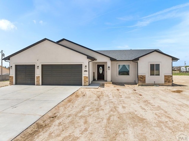 ranch-style house featuring a garage, driveway, stone siding, and stucco siding