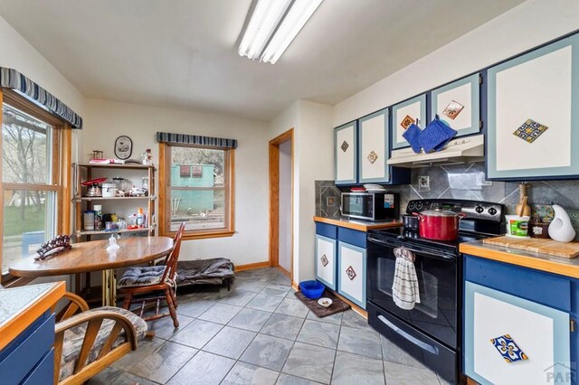 10511 Apache City Rd, Rye, CO 81069 - kitchen featuring under cabinet range hood, light tile patterned flooring, stainless steel microwave, black electric range, and backsplash