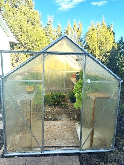 exterior space featuring a greenhouse and an outdoor structure