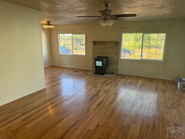 unfurnished living room featuring ceiling fan, a textured ceiling, baseboards, and wood finished floors