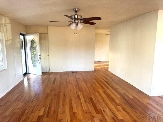 interior space featuring dark wood-type flooring, ceiling fan, and baseboards