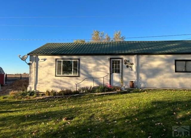 back of property with metal roof and a yard