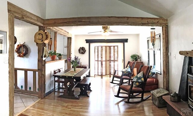 dining room with beamed ceiling, light wood-type flooring, and a ceiling fan