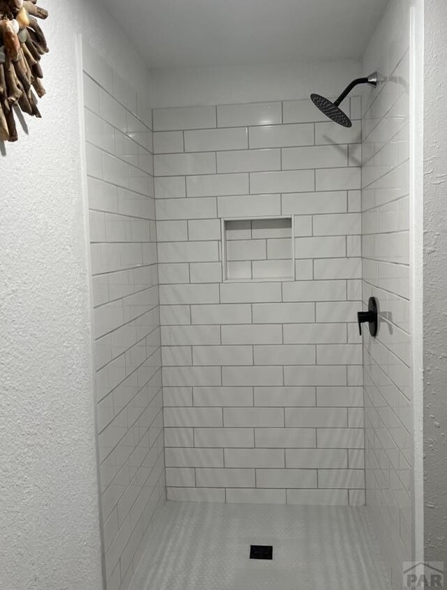 full bath with a shower stall and a textured wall