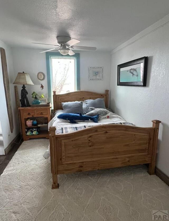 carpeted bedroom featuring ceiling fan and a textured ceiling