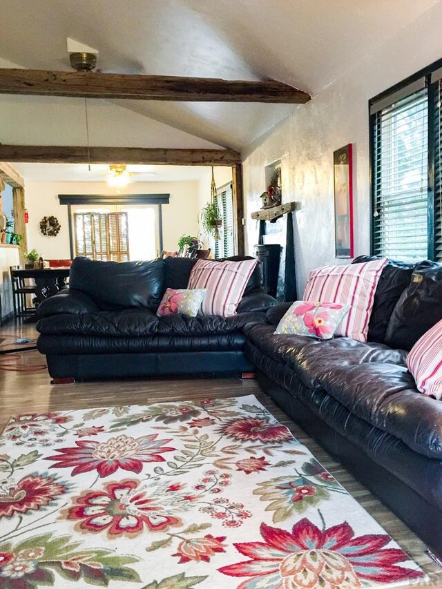 living area featuring lofted ceiling with beams, plenty of natural light, and wood finished floors