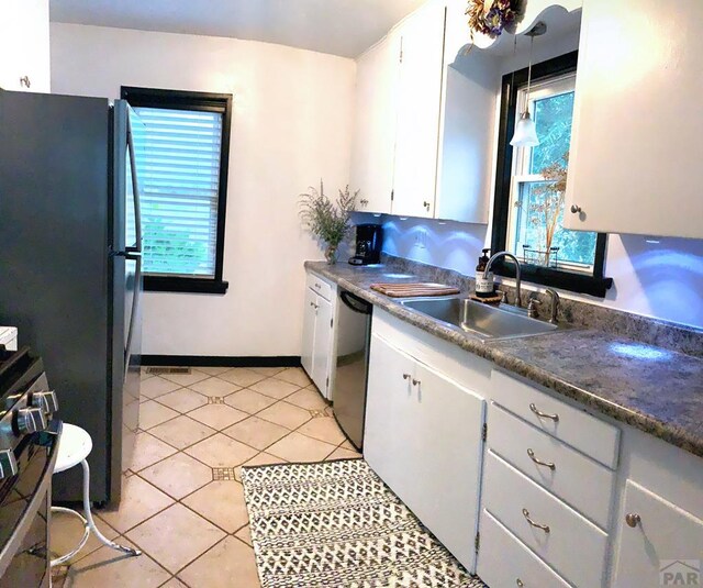 kitchen featuring dark countertops, dishwashing machine, white cabinets, and a sink