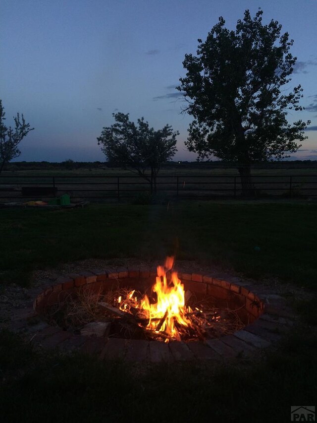 view of yard with fence, a fire pit, and a rural view