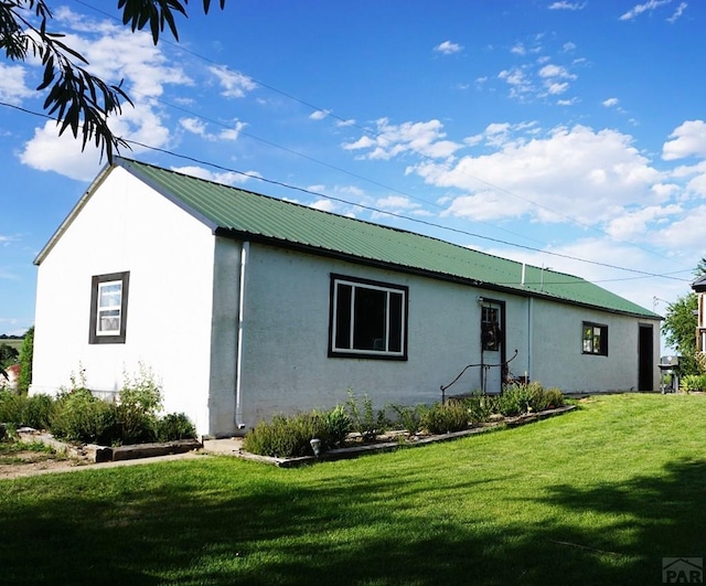 exterior space featuring metal roof, a yard, and stucco siding