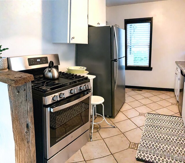 kitchen with stainless steel appliances, baseboards, white cabinets, and light tile patterned flooring