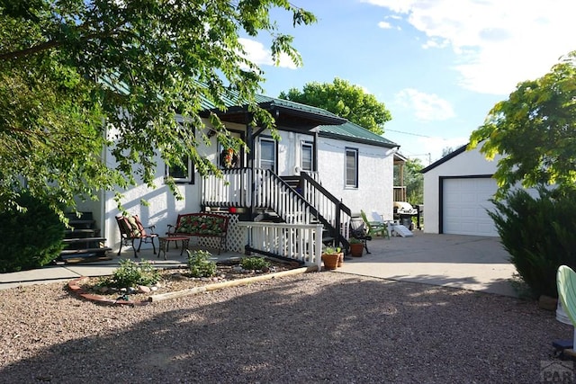 view of front facade with a garage, driveway, stairway, metal roof, and an outbuilding