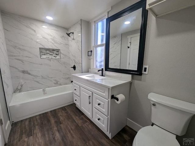 bathroom featuring baseboards, toilet, wood finished floors, bathtub / shower combination, and vanity