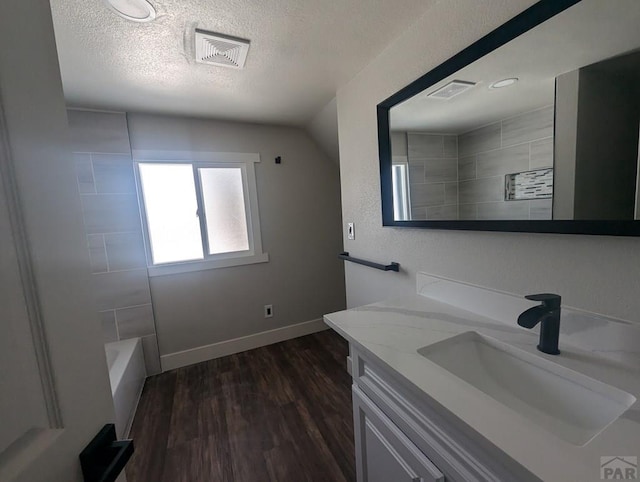 full bath featuring a textured ceiling, wood finished floors, vanity, and visible vents