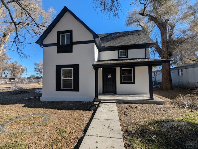 view of front of home with roof with shingles, a porch, and stucco siding