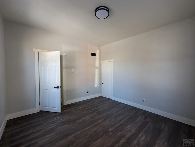 unfurnished bedroom with dark wood finished floors and baseboards