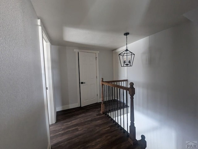 stairs featuring an inviting chandelier, wood finished floors, and baseboards