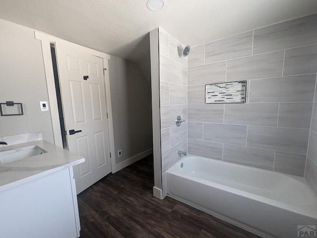 bathroom with baseboards, bathing tub / shower combination, vanity, and wood finished floors