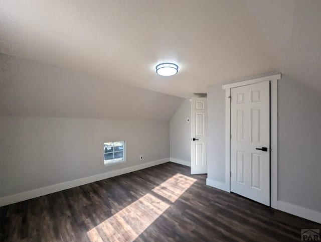 additional living space featuring dark wood-style floors, baseboards, and vaulted ceiling