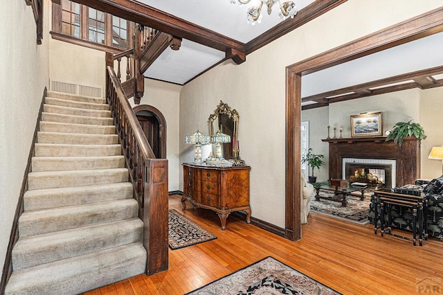 stairs featuring baseboards, wood finished floors, a multi sided fireplace, and crown molding