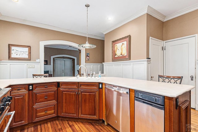 kitchen featuring arched walkways, dishwasher, decorative light fixtures, light countertops, and a sink