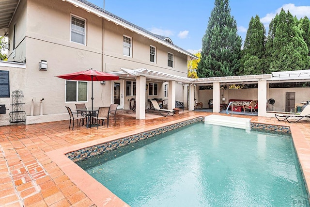 back of house featuring an outdoor pool, stucco siding, a patio, and a pergola