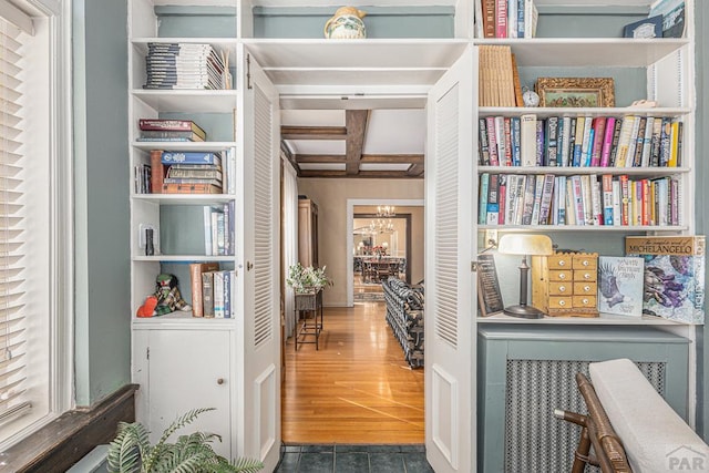 hall with dark wood finished floors, beam ceiling, coffered ceiling, and a notable chandelier