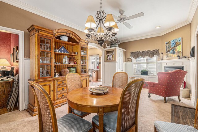 dining area featuring ornamental molding, arched walkways, and light colored carpet