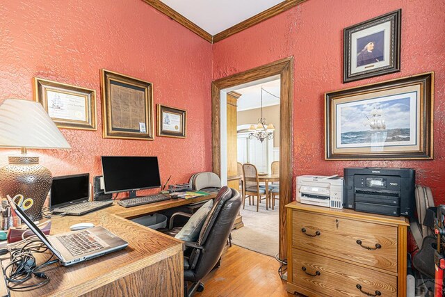 office space featuring light wood finished floors, ornamental molding, a chandelier, and a textured wall