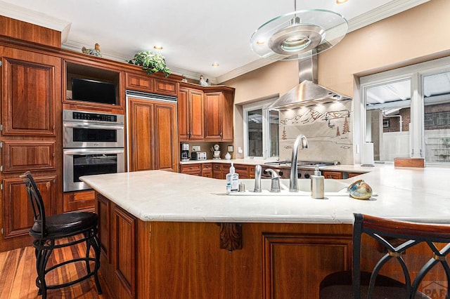 kitchen featuring stainless steel appliances, a breakfast bar, light countertops, and crown molding