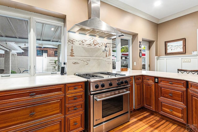 kitchen with extractor fan, high end stove, light countertops, light wood finished floors, and crown molding