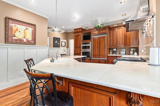 kitchen featuring range, brown cabinets, light countertops, pendant lighting, and a sink