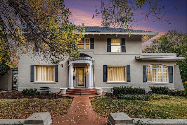 view of front of home featuring a shingled roof, a balcony, and stucco siding