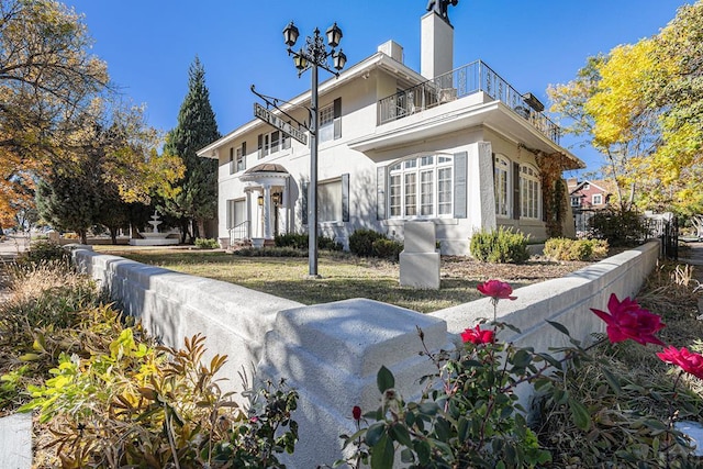 exterior space with a chimney, a balcony, and stucco siding